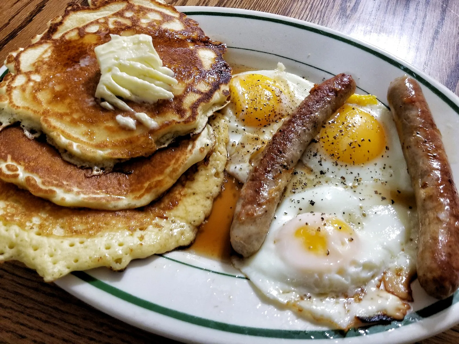 Pancakes with sausage and eggs on a breakfast plate.