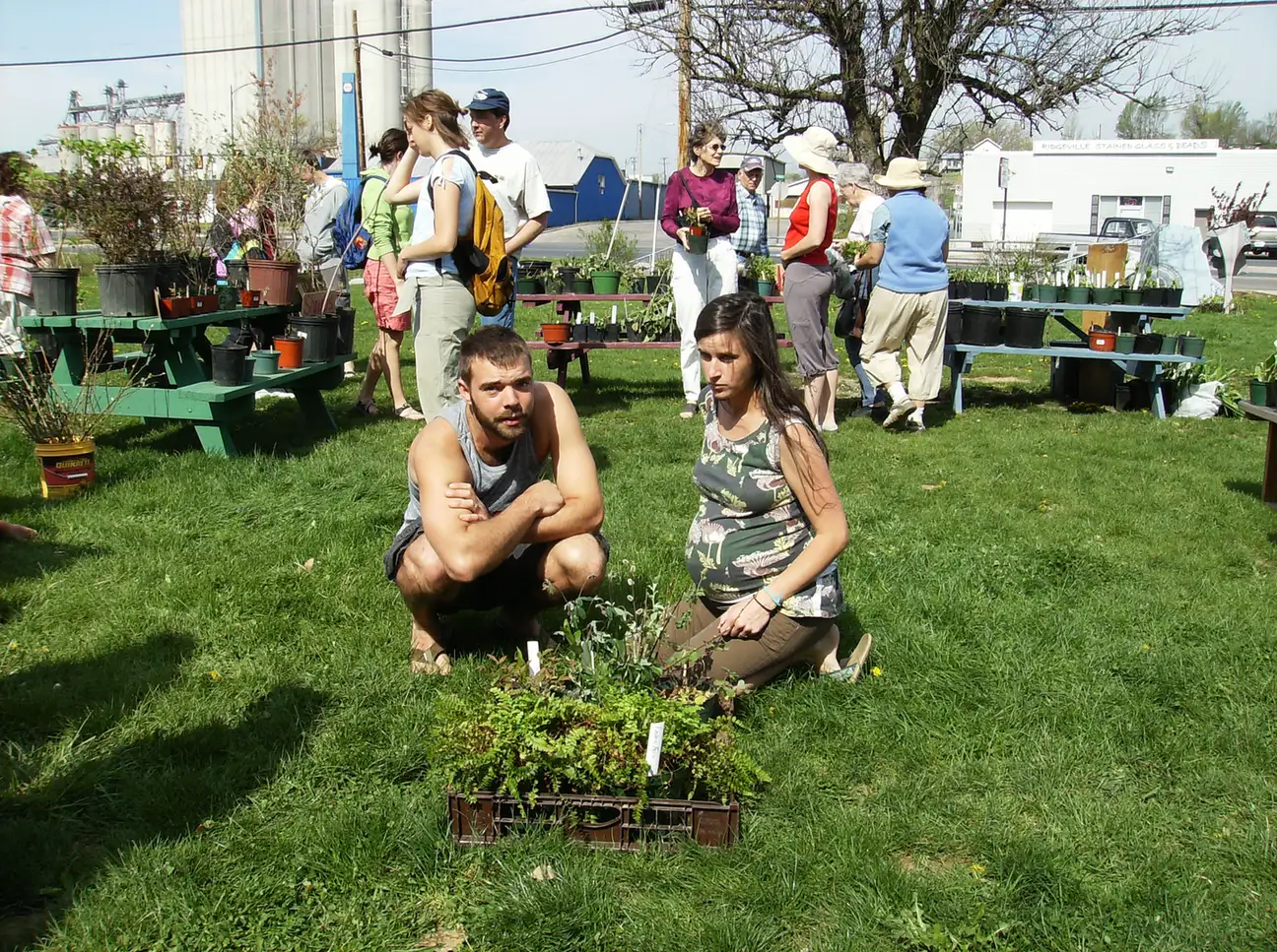 Shoppers look over potted plants on the lawn at a community plant sale in Harrisonburg, Virginia.