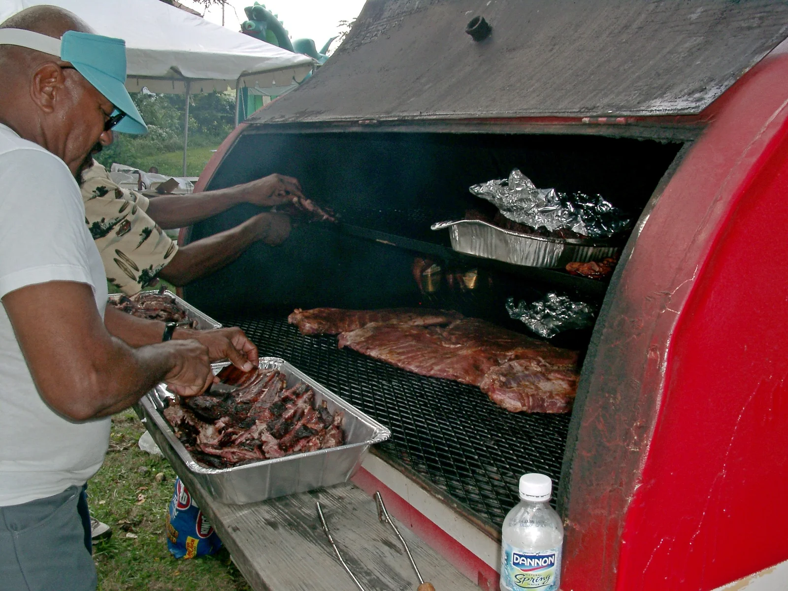 Volunteers tend ribs and chicken in a trailer smoker at a community barbecue in Kansas City, Missouri.