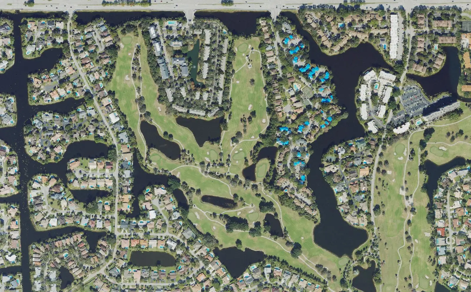 Homes along the lakes and fairways of the golf course in the middle of Jacaranda, seen from above.