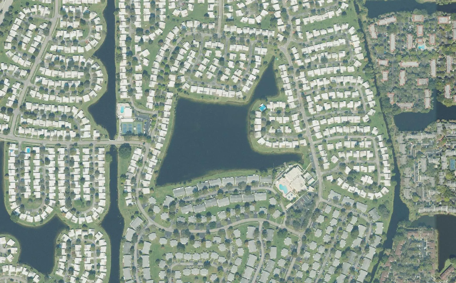 Rows of Lauderdale West homes curving around the community's central lake in Plantation, seen from above.