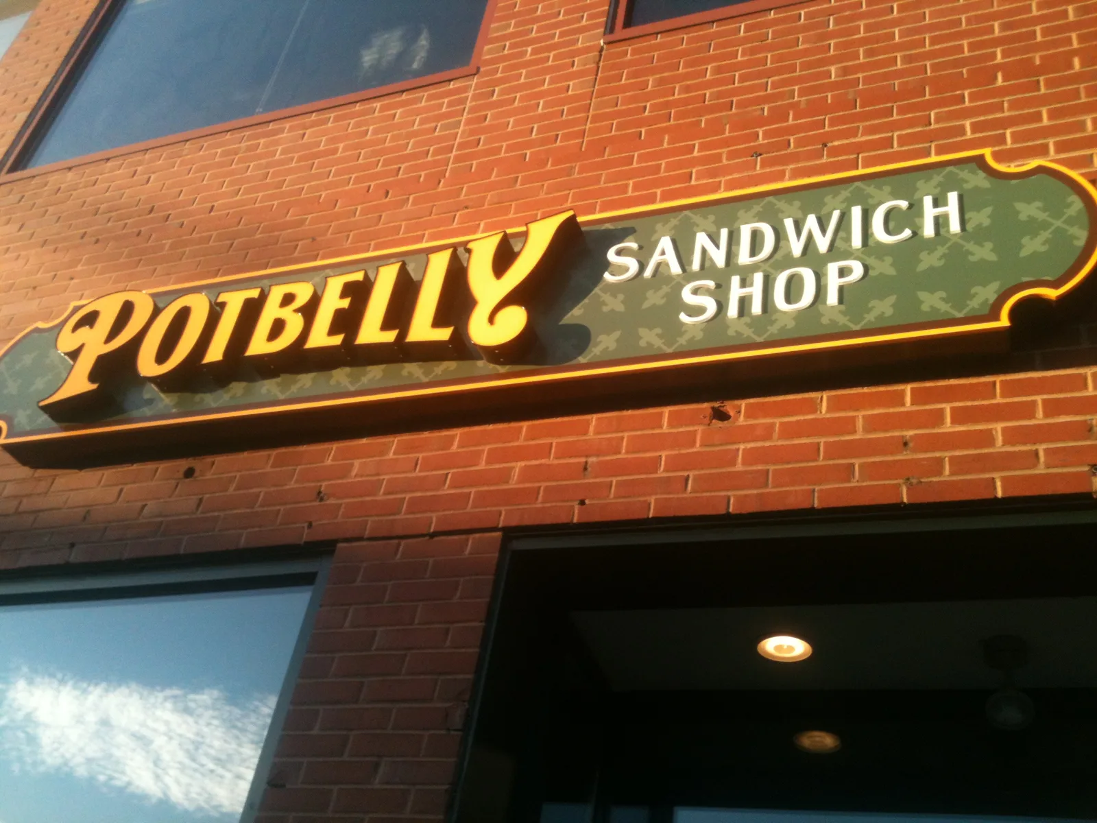 A Potbelly Sandwich Shop sign over a store entrance. The picture shows another Potbelly location, not the Plantation shop.