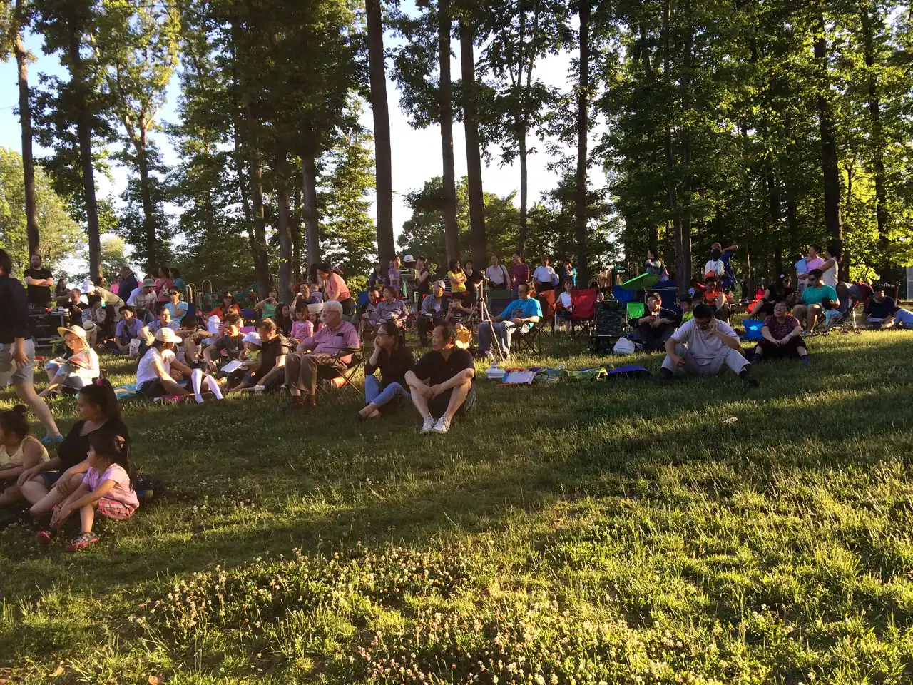 Families sit on blankets and lawn chairs at a free summer concert in Ossian Hall Park in Annandale, Virginia.